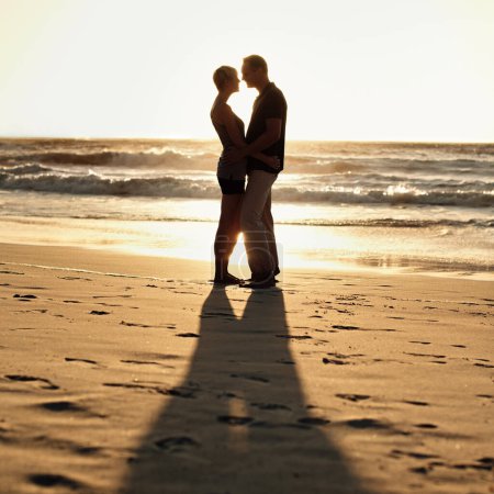 Foto de Silueta, pareja y beso en la playa al atardecer para una escapada romántica, con cita y fin de semana en Turquía. Mujer, hombre o personas enamoradas de abrazo para caminar, vinculación o juntos en la relación de cuidado feliz. - Imagen libre de derechos
