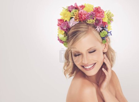 Photo for Woman, face and flowers on crown in studio with makeup and happiness for cosmetics, beauty and skincare. Spring aesthetic, model and floral headband with mockup space and wellness on white background. - Royalty Free Image