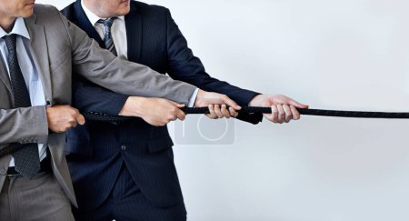 Photo for Hands, partnership and tug of war with businessmen in studio for collaboration, competition or effort. Teamwork, rope and challenge with corporate people pulling together for strength or struggle. - Royalty Free Image
