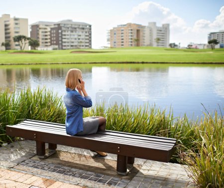 Photo for Phone call, park and woman on bench in city for communication, social networking and chat outdoors. Relax, happy and person on smartphone for talking, conversation and speaking by lake on weekend. - Royalty Free Image