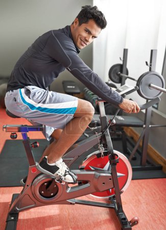 Photo for Fitness, bicycle and portrait of man in gym for cycling marathon, race or competition training. Fitness, health and athlete riding spinning machine for cardio workout or exercise in sports center - Royalty Free Image
