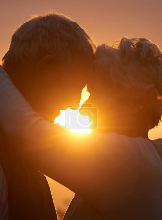 Photo for Sunset, senior couple and embrace outdoor, care and bonding for connection together in nature. Man, woman and touch forehead for love, romance and hug for commitment to relationship in retirement. - Royalty Free Image