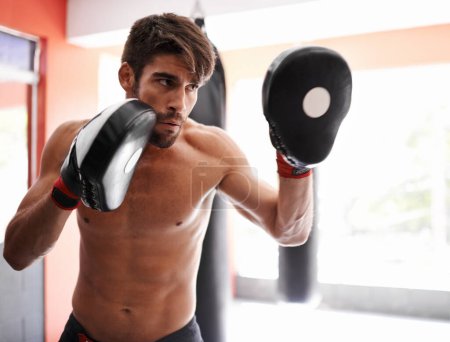 Gym, boxing and man with sparring pads for fitness, exercise and mixed martial arts training. Sports, fight and kickboxer with practise mitts for challenge, workout or gear for power, battle or focus