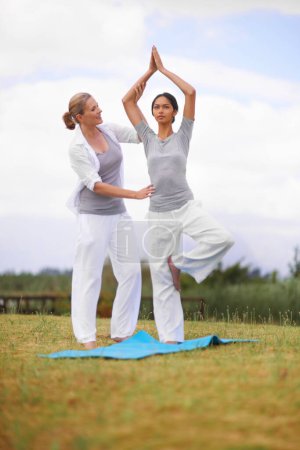 Téléchargez les photos : Femme, entraîneur personnel et yoga sur le terrain dans la nature pour le bien-être spirituel, namaste ou bien-être. Jeune femme, yogi ou professeur de fitness en zen, équilibre ou étirement sur tapis en plein air. - en image libre de droit