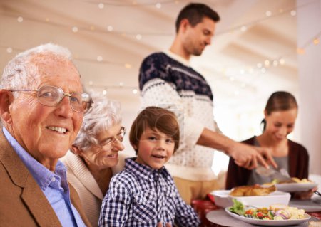 Téléchargez les photos : Grand-parents, portrait et famille au dîner de Noël, ainsi que la nourriture et la célébration à la maison. Heureux, événement et enfant sourire avec vieil homme au déjeuner et se détendre en vacances à table avec grand-mère. - en image libre de droit