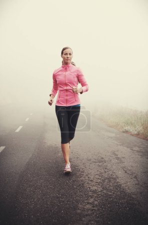 Photo for Nature, fitness and young woman running on mountain road for race, marathon or competition training. Sports, exercise and female athlete with cardio workout in misty outdoor woods or forest - Royalty Free Image