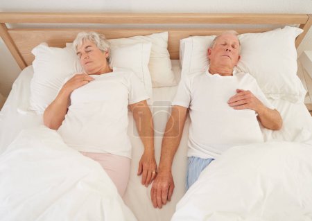 Photo for Sleeping, love and senior couple in bed, resting and relaxing together on weekend in bedroom. Elderly people, retirement and dreaming at home, top view and support in marriage or relationship and nap. - Royalty Free Image