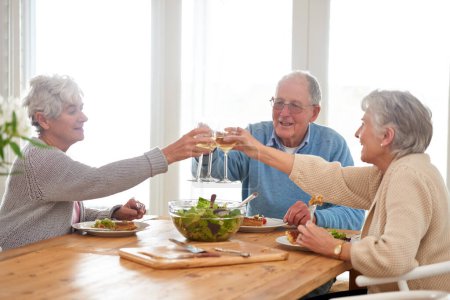 Wein, Prost und Senioren beim Brunch zu Hause mit Lächeln, Feiern und Zusammenhalt im Ruhestand. Essen, Trinken und Toast mit Glas, alter Mann und Frauen am gemeinsamen Tisch zum fröhlichen Mittagessen