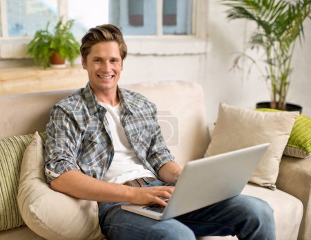 Photo for Laptop, relax and portrait of man on sofa in home for watching videos, networking and browse website. Happy, smile and person with computer for internet, remote work and streaming in living room. - Royalty Free Image