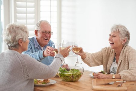 Téléchargez les photos : Vin, pain grillé et amis aînés au déjeuner à la maison avec sourire, célébration et collage à la retraite. Nourriture, boissons et acclamations avec verre, vieil homme et femmes à table pour un brunch heureux - en image libre de droit