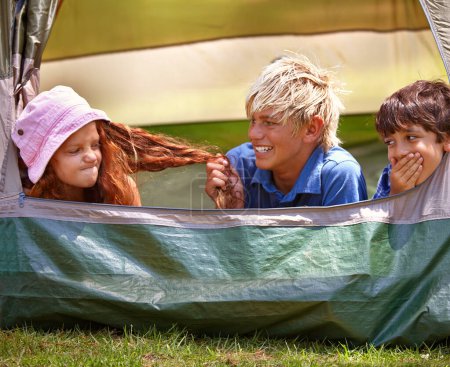 Photo for Kids, camp and outdoors for tent, friends and nature on summer vacation with boys pulling person hair. Children, annoyed girl and holiday for adventure, tease and camping in backyard and on grass. - Royalty Free Image