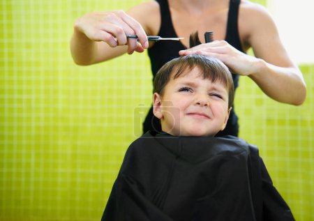 Photo for Child, boy and barber with haircut at salon for grooming, hairstyle and unhappy with scissors. Hairdresser, person and kid for hair treatment, haircare and hairdressing with comb or sitting on mockup. - Royalty Free Image