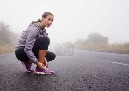 Photo for Fitness, woman and tie shoes on road outdoor to prepare for exercise, training or workout with fog in winter. Sports, serious person and tying sneakers, thinking and getting ready on mockup space. - Royalty Free Image