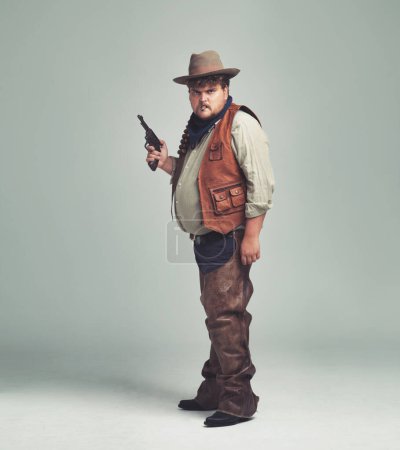Photo for Portrait, man and cowboy with a gun, serious and proud person on white studio background. Face, model and guy with pistol or firearm with danger or warning with Halloween costume, confidence or Texas. - Royalty Free Image