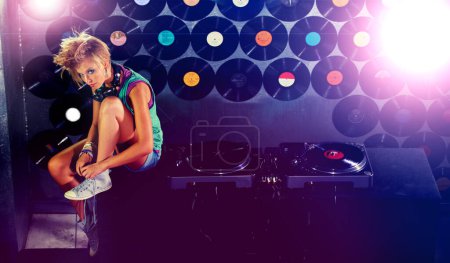 Photo for Woman, dj and portrait on stage with turntable in night club, sitting and wall of vinyls for music event. Female producer, mixer and headphones with record player for rave party and entertainment. - Royalty Free Image
