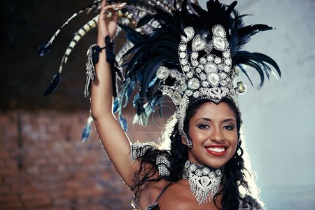 Portrait, samba dancer and black woman with headdress for carnival, festival or parade on urban background in Rio de Janeiro. Brazilian performer, female person and closeup in costume for performance.