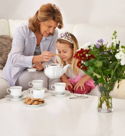 Photo for Grandmother, daughter and happy for tea party in living room with bonding, playing and breakfast or brunch at home. Excited senior woman, family and kid with teapot, biscuits or princess for learning. - Royalty Free Image