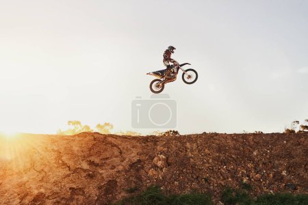 Photo for Person, jump and motorcyclist in the air on mockup with sunset for trick, stunt or ramp on outdoor dirt track. Expert rider on motorbike with lift off for extreme sports or rally challenge in nature. - Royalty Free Image