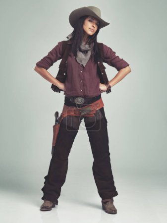 Photo for Woman, cowgirl and portrait in studio for western costume with confidence on grey background, weapon or outlaw. Female person, wild and hat with mockup space in Texas for dress up, old west or rodeo. - Royalty Free Image
