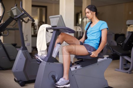 Woman, fitness and exercise bike in gym, wellness and stationary machine for workout at club. Female person, cardio and cycling for strength training, athlete and equipment for challenge and health.