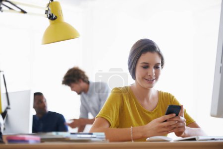Photo for Woman, smartphone and online at desk, smiling at device for notification.Digital, technical career and creative web design with happy employee, scrolling and browsing internet on social media. - Royalty Free Image