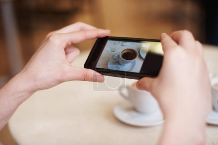 Photo for Cellphone, hands and photography of coffee in restaurant and online to review a cappuccino. Person, mobile app and post of espresso for social media followers and influencer with drink in close up. - Royalty Free Image