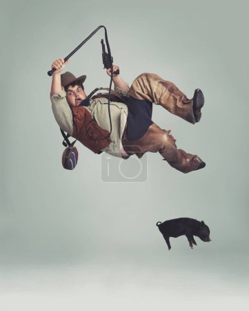Photo for Cowboy, accident and man catching pig for texas culture in studio on gray background with space. Western, animal or noose and clumsy young person in costume with fail, mistake or oops for falling. - Royalty Free Image