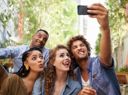 Téléchargez les photos : Drôle, visage et groupe d'amis pour selfie sur le campus universitaire pour mise à jour de photo de profil ou post sur les médias sociaux. Hommes, femmes et étudiants heureux avec la technologie pour la mémoire, la diversité et le plaisir collégial. - en image libre de droit