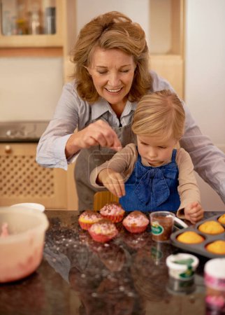 Photo for Help, grandmother and child in kitchen for baking cupcake with sprinkle. Home, chef for growth and development with family and creativity for dessert ingredients, smile for fun activity apron. - Royalty Free Image