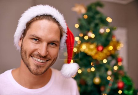 Téléchargez les photos : Homme, sourire et chapeau pour Noël, portrait et maison avec bokeh sur l'arbre pour la célébration festive en vacances pour la saison. Homme, heureux et excité avec joie sur le visage pour se détendre à la maison pour la pause. - en image libre de droit
