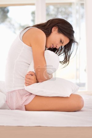 Photo for Woman, stomachache and period pain on bed, cramps and appendicitis in home for discomfort. Female person, pillow and constipation or ulcer in bedroom, muscle strain and bloating or menstrual crisis. - Royalty Free Image
