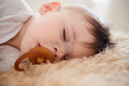 Téléchargez les photos : Bébé, sommeil et sucette avec détente à la maison pour un développement sain, la croissance et fatigué dans la chambre. Enfant, repos et mannequin dans la bouche avec sieste, rêve et bien-être dans la crèche de la maison ou de l'appartement. - en image libre de droit