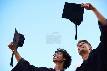 Photo for Graduation, university and students with hats in sky for learning, studying and knowledge on academy campus. Education, friends and happy men throw for celebration, graduate ceremony and college. - Royalty Free Image