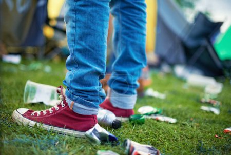 Foto de Pies, evento y una persona con basura en la hierba y botellas de plástico, latas en un festival al aire libre. Gente en una fiesta, concierto con basura en un campo y zapatos con contaminación para reciclar basura. - Imagen libre de derechos