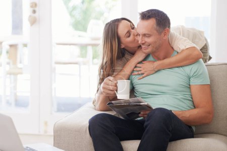 Photo for Happy couple, kiss and newspaper with coffee in home, romantic and bonding together with love in marriage. Man, woman and surprise by touch with relax, warm drink and care by sofa in modern apartment. - Royalty Free Image