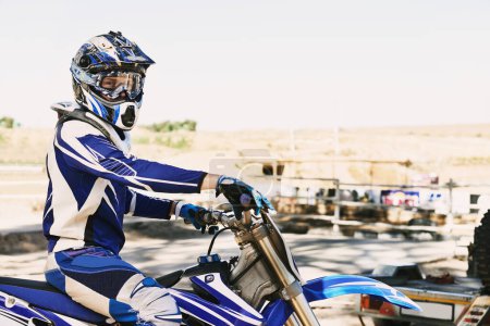 Photo for Dirtbike, extreme sport and portrait for man in helmet for competition, race and games with safety. Person, motorcycle and outdoor for contest, motor cross and fast transport with speed in desert. - Royalty Free Image