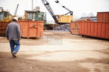 Photo for Crane, machine and engineer man in junkyard to recycle metal for sustainability, manufacturing or pollution. Vehicle, tractor and outdoor in scrapyard for ecology with back, industry and environment. - Royalty Free Image