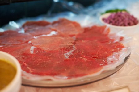 Carpaccio, closeup and food on plate for dinner with appetizer, fine dining and buffet of raw meat in restaurant. Beef, seafood and protein meal on table for nutrition, snack or lunch at social event.