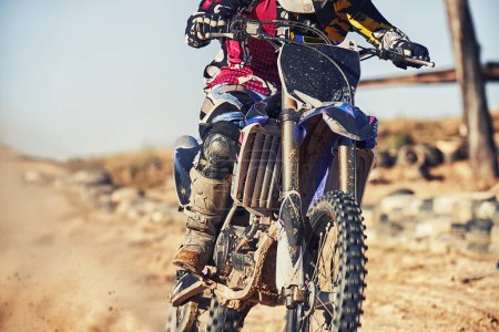 Person, motorcyclist and track with dirt bike for race, extreme sports or outdoor competition. Closeup or legs of expert rider on motorbike, scrambler or sand course for off road rally challenge.