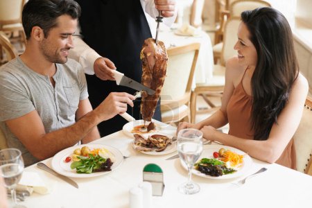 Photo for Happy couple, date and waiter cutting kebab for serving, fine dinning or romantic dinner at table. Young man and woman with chef or skewer of food for meal, eating or enjoying service at restaurant. - Royalty Free Image