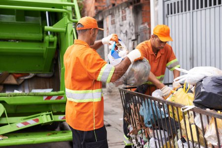 Photo for City, trash and people with garbage truck working in waste management and maintenance service. Urban, cleaning and men outdoor with industrial sanitation, collection of rubbish and infrastructure. - Royalty Free Image