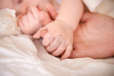 Photo for Bed, holding hands and parent with infant, care and support with maternity, health and wellness at home. Fingers, family and love with a healthy baby, protection and child development with bonding. - Royalty Free Image