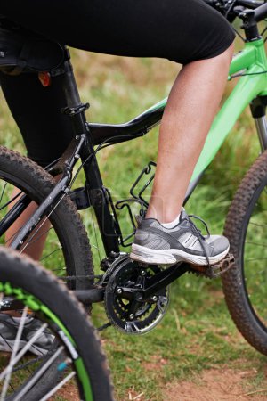Photo for Person, legs and cyclist with bicycle in nature for paddling, cycling or outdoors sports in health and wellness. Closeup of biker, foot or shoes on mountain bike for off road travel, ride or fitness. - Royalty Free Image