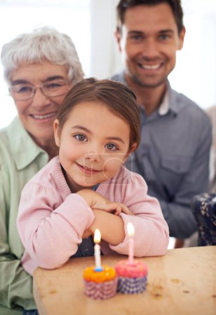 Photo for Girl kid in portrait, birthday party and cupcake with candle for celebration, family and smile for special event at home. Grandmother, father and child with happy people for anniversary and dessert. - Royalty Free Image
