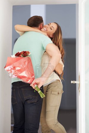 Photo for Man, surprise or flowers for woman by front door, hug or happy couple to celebrate love in home. Husband, care or grateful with floral present for wife, gratitude for bonding together on anniversary. - Royalty Free Image