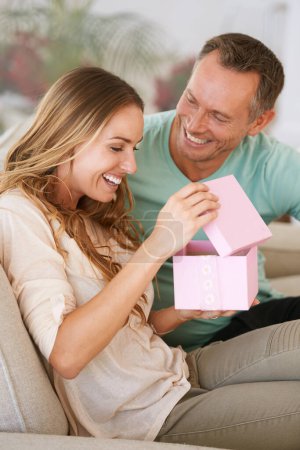 Woman open gift, man and happiness with surprise for birthday or anniversary, love and support with romance. Couple in marriage, unboxing package with ribbon and present for token of appreciation.