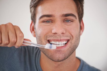 Face, man brushing teeth and toothbrush for dental and wellness, fresh breathe and tooth whitening in morning routine. Clean mouth, toothpaste and oral care with orthodontics and hygiene in portrait.