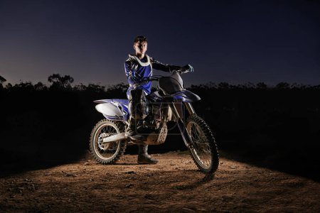 Photo for Extreme sport, portrait and man with dirt bike, confidence and gear for competition, race or challenge. Adventure, adrenaline and serious face of athlete on course with off road motorbike at night. - Royalty Free Image