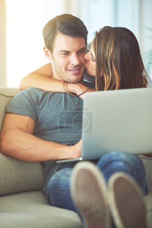 Photo for Kiss, computer and woman hugging man on sofa networking on social media, website or internet. Happy, love and female person embracing husband reading online blog with laptop in living room at home - Royalty Free Image