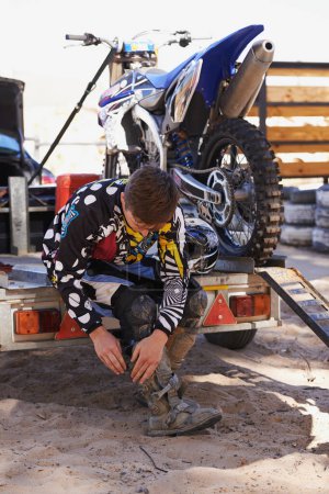 Photo for Motorbike, race and sports with man getting ready for off road adrenaline, competition or training outdoor. Boots, adventure and dirtbike hobby with person in gear on trailer for performance. - Royalty Free Image